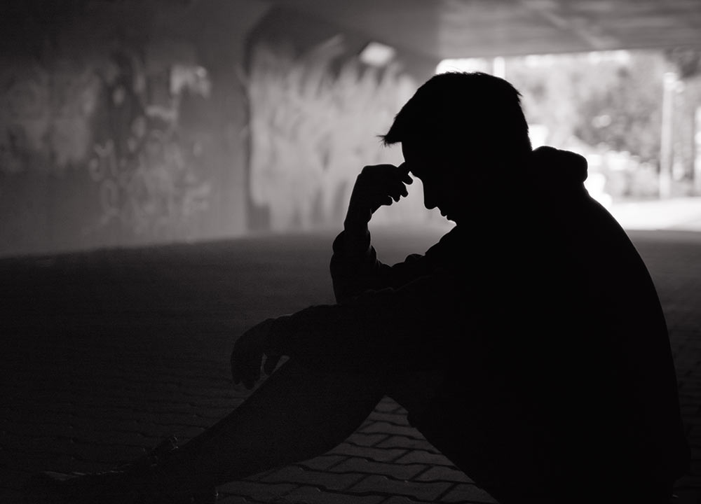 Image of a man sitting in an alley in the dark. This image exemplifies how a substance abuse counselor could provide support to this person with addiction counseling in Birmingham, AL. | 35223
