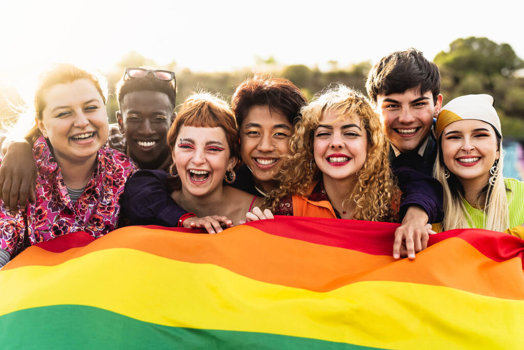 Group of LGBTQ+ youth holding a gay pride flag supporting each other. LGBTQ+ youth face their own set of unique challenges. Depression therapy in Birmingham, AL can help overcome these issues. 