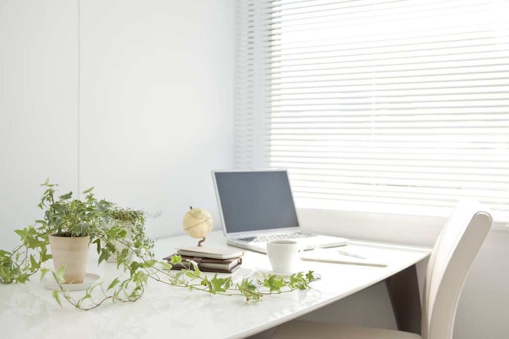 Desk with a plant, laptop and planner setting on it representing the perfect environment to utilize for online therapy in Alabama. 