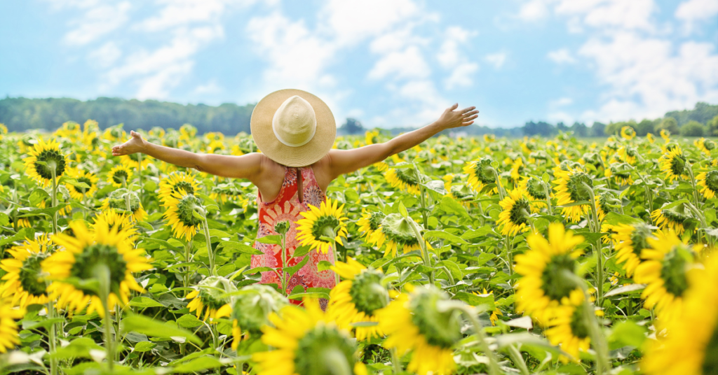 A woman standing in a field of sunflowers with her arms outstretched in joy representing someone who has overcome the cycle of co-dependency through Counseling for Codependency in Birmingham, AL.