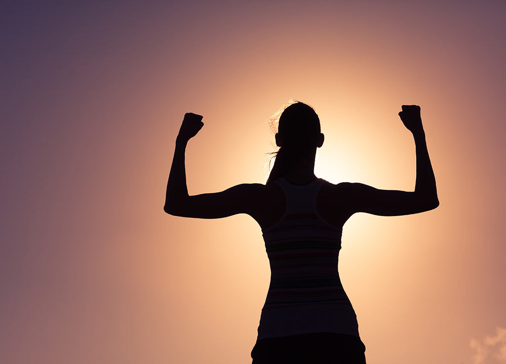 A woman stands with her arms raised triumphantly in celebration of overcoming her trauma with the help of Trauma Counseling in Birmingham, AL. 