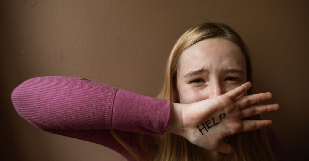 a young female crying with the word help written on hand/ trauma therapy/ empower counseling/ 35223 35209 35216