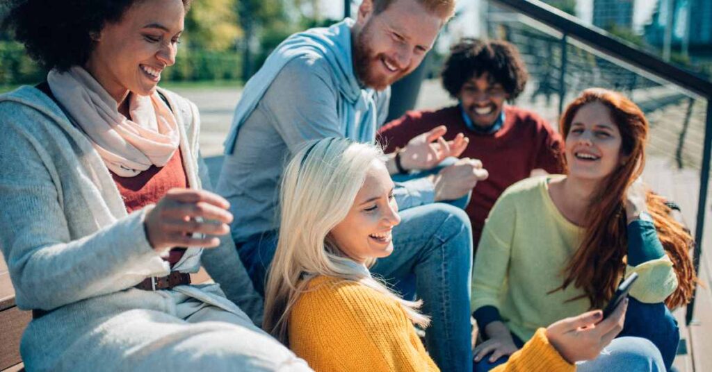 Group of young adults looking happy while sitting together outside. You can feel hopeful and happy after ACT Treatment for Anxiety in Birmingham, AL here.