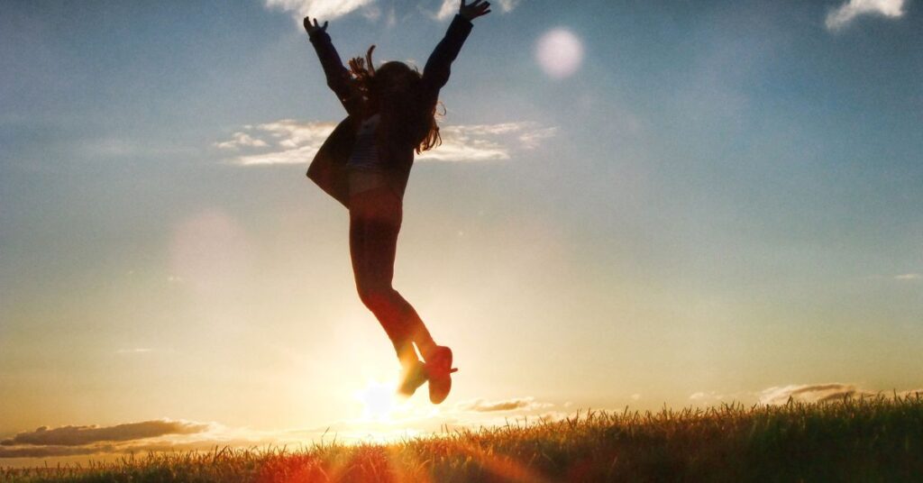 Woman jumping for joy outside. Feel happy and joyful with an ACT treatment plan for anxiety with a Birmingham therapist here. 