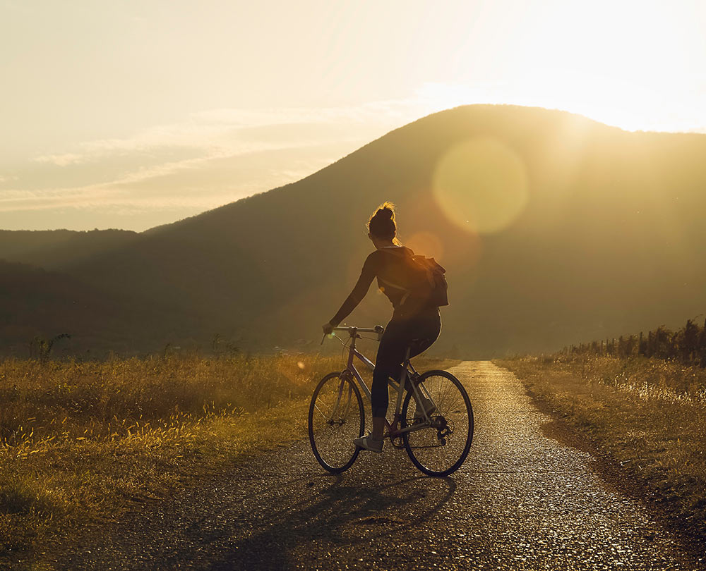 A woman cycles through the countryside. She is feeling much happier after beginning counseling for life transitions in Birmingham,AL 35532 with Empower Counseling.