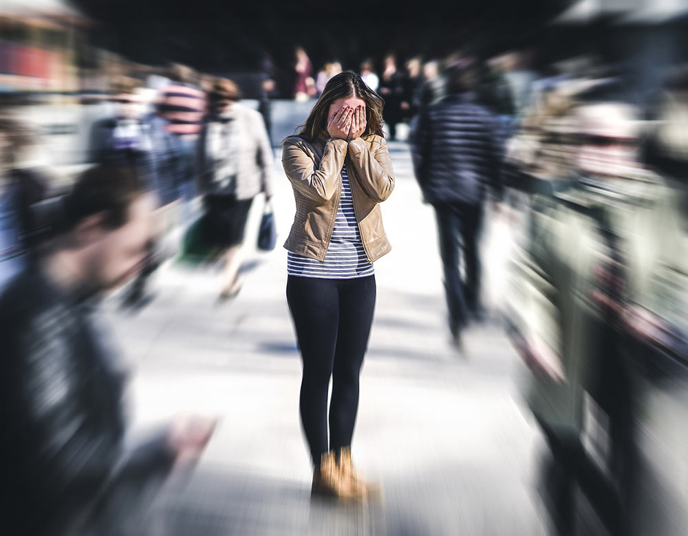 A woman stands in a crowd having a panic attack. She has decided it's time to start counseling for life transitions in Birmingham, AL 35532 with a counselor at Empower Counseling.