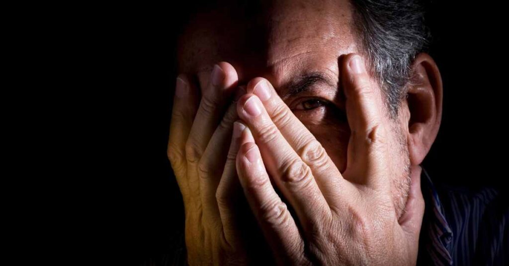 a man hiding face in hands before therapy to banish imposter syndrome/ therapists Birmingham Al./ Empower Counseling