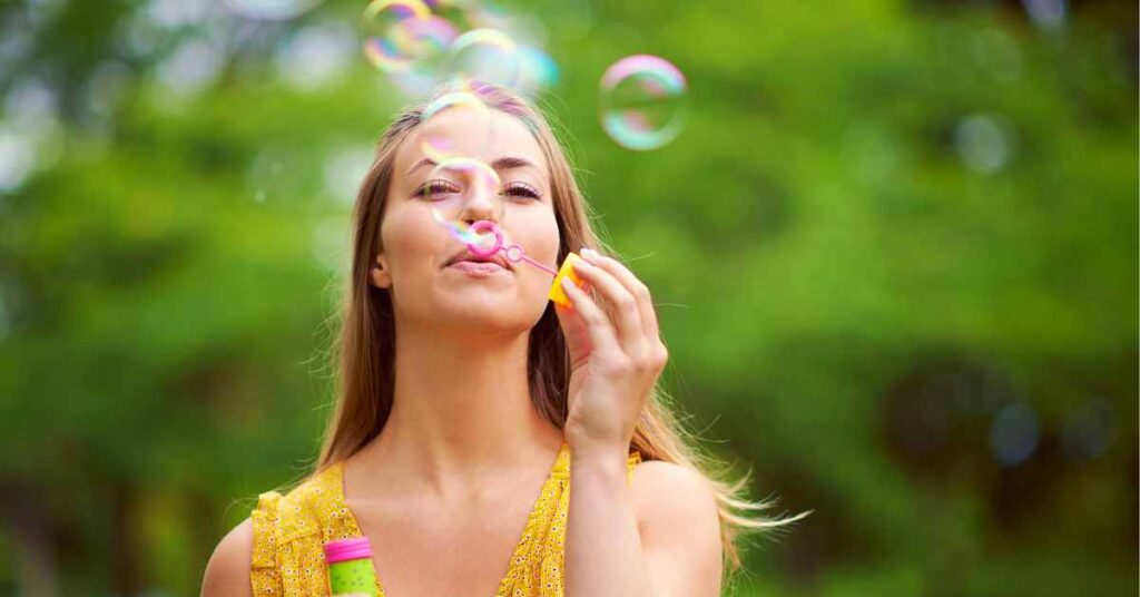 a happy woman blowing bubbles/ Overcome self-criticism/ Empower Counseling/ birmingham Al