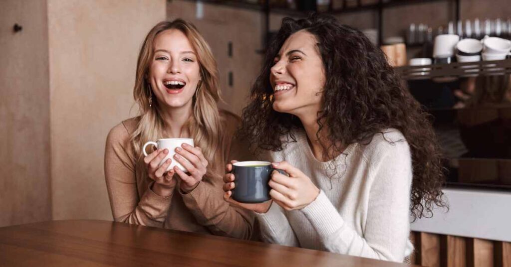 Two female friends laughing over coffee