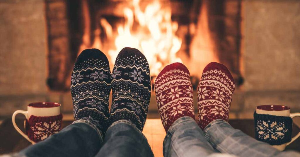 two people warming feet by fire/ reduce holiday stress/ Empower Counseling/ Birmingham  AL