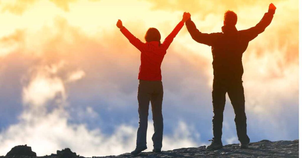A man and woman with triumphant outstretched arms who have become the best version of themselves through therapy in Birmingham, Al/ Empower Counseling 