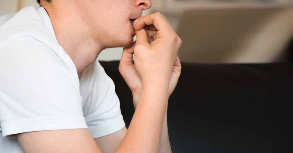 A man with anxiety biting his nails before meeting an anxiety therapist in Birmingham Al/ Empower Counseling/ Mountain Brook