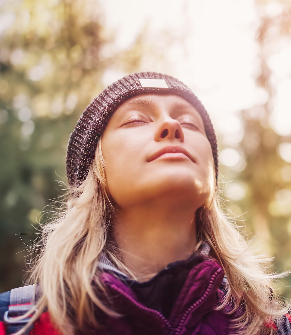 Image of a peaceful blonde woman closing her eyes while hiking in the forest. Find peace from your past trauma with the help of EMDR therapy in Birmingham, AL.