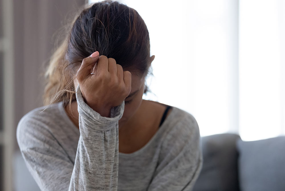 Image of a upset woman resting her forehead on her hand. If you're struggling with anxiety due to trauma, learn how EMDR therapy in Birmingham, AL can help!