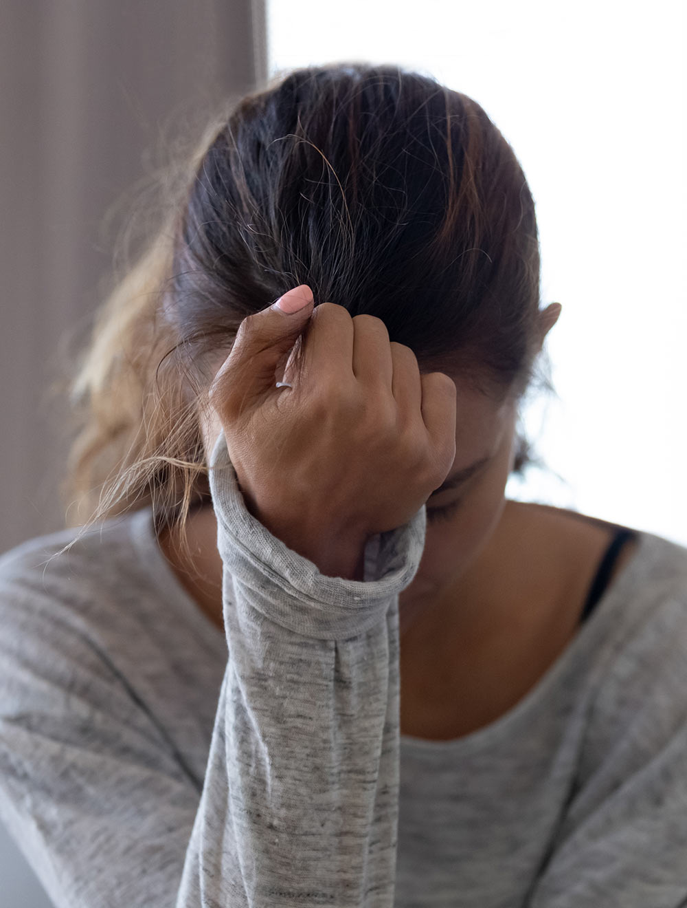 Image of a distressed woman resting her forehead on her hand. Learn how EMDR therapy in Birmingham, AL can help you cope with your past trauma.